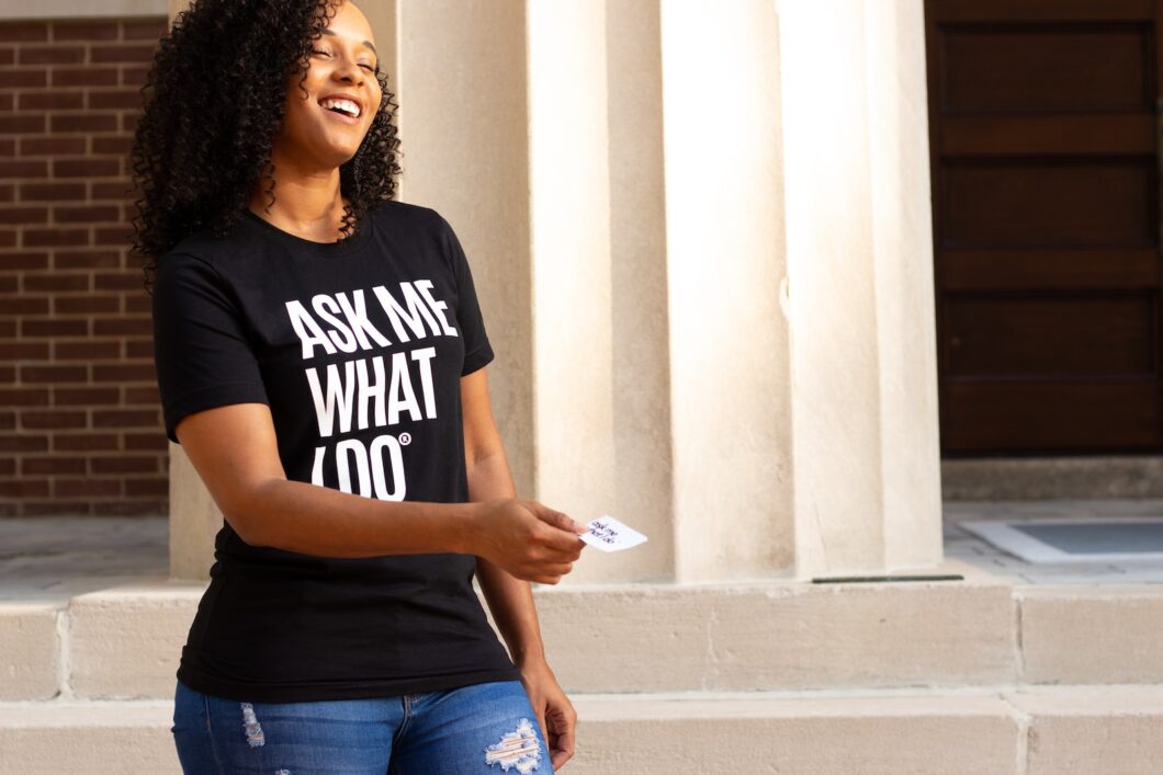 woman in black crew neck t-shirt and blue denim shorts leaning on white concrete wall