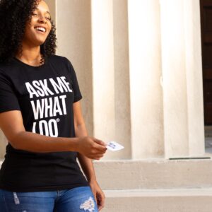 woman in black crew neck t-shirt and blue denim shorts leaning on white concrete wall